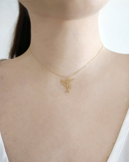 close up of a woman's neck wearing a gold necklace with a cutout  origami style pendant in the shape of a hummingbird