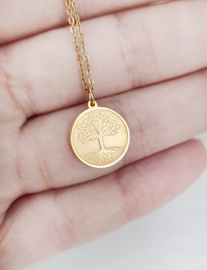 close up of a palm holding a yellow gold necklace with a disc pendant engraved with the Tree of Life for size reference