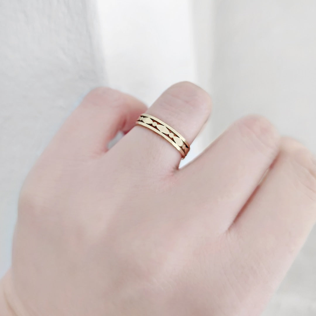 Gold art deco ring on a person's finger against a light background
