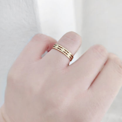 Gold art deco ring on a person's finger against a light background