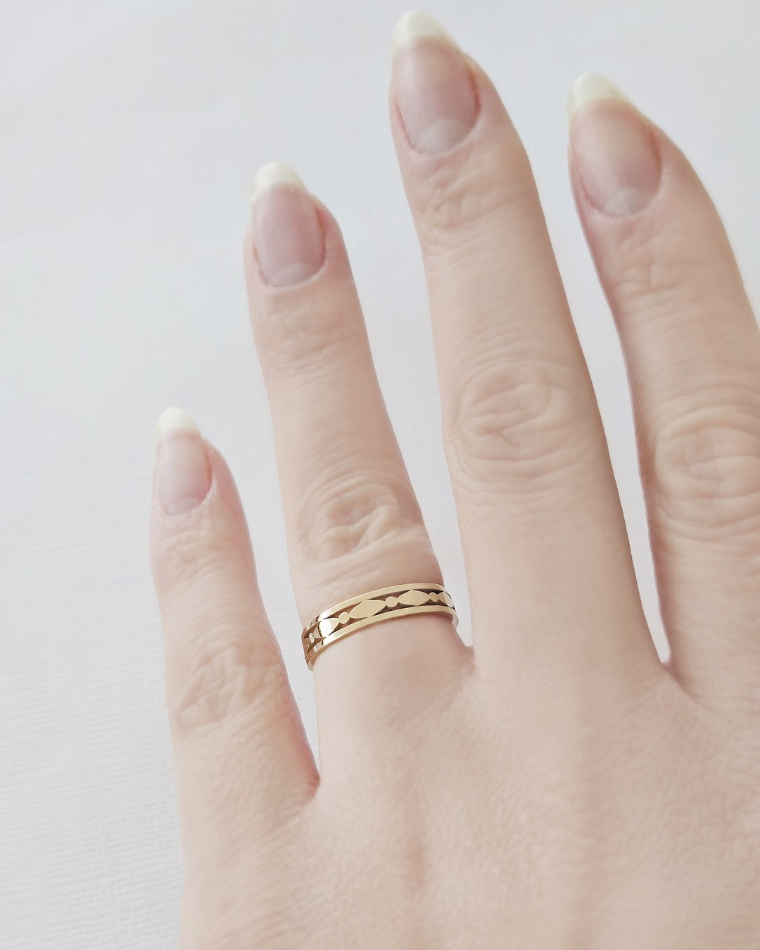 Female hand wearing a solid yellow gold art deco band 