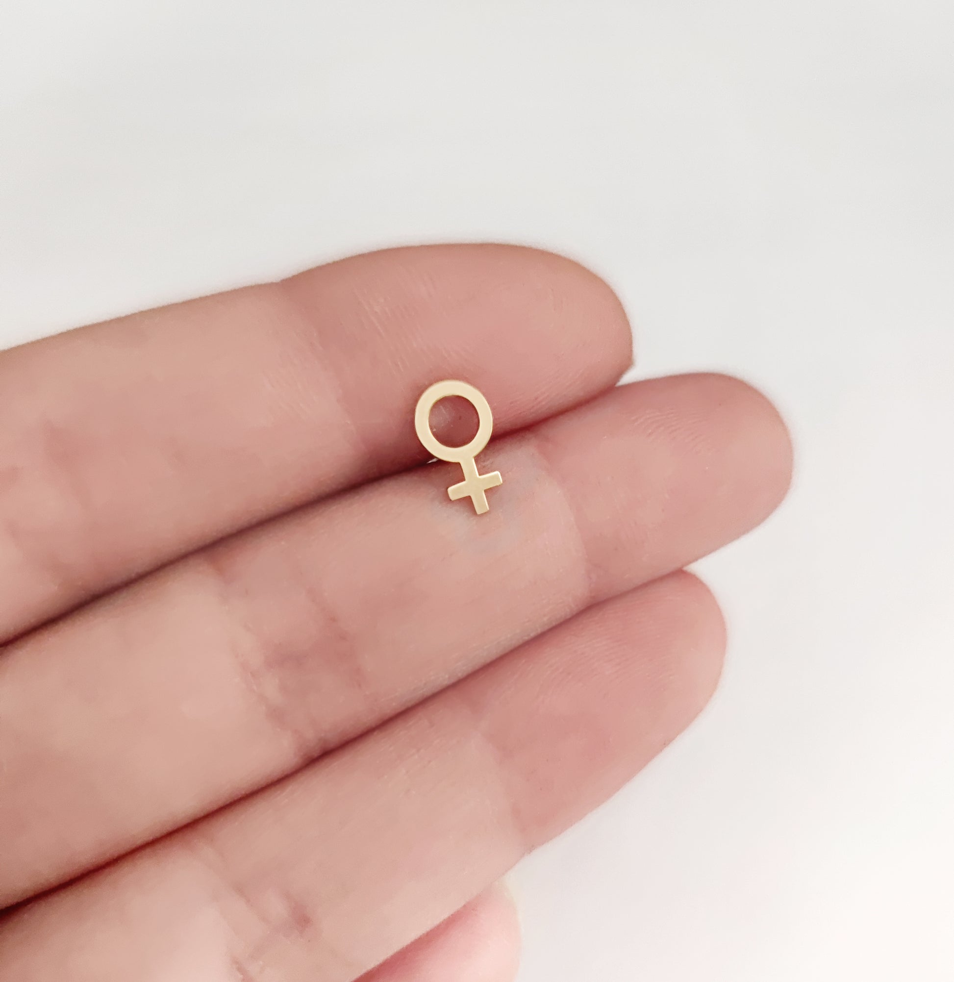 female/Venus symbol stud earring held on hand for size reference