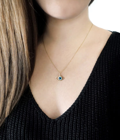 Female wearing a gold necklace with an eye-shaped pendant featuring a blue eye in the center surrounded by diamonds