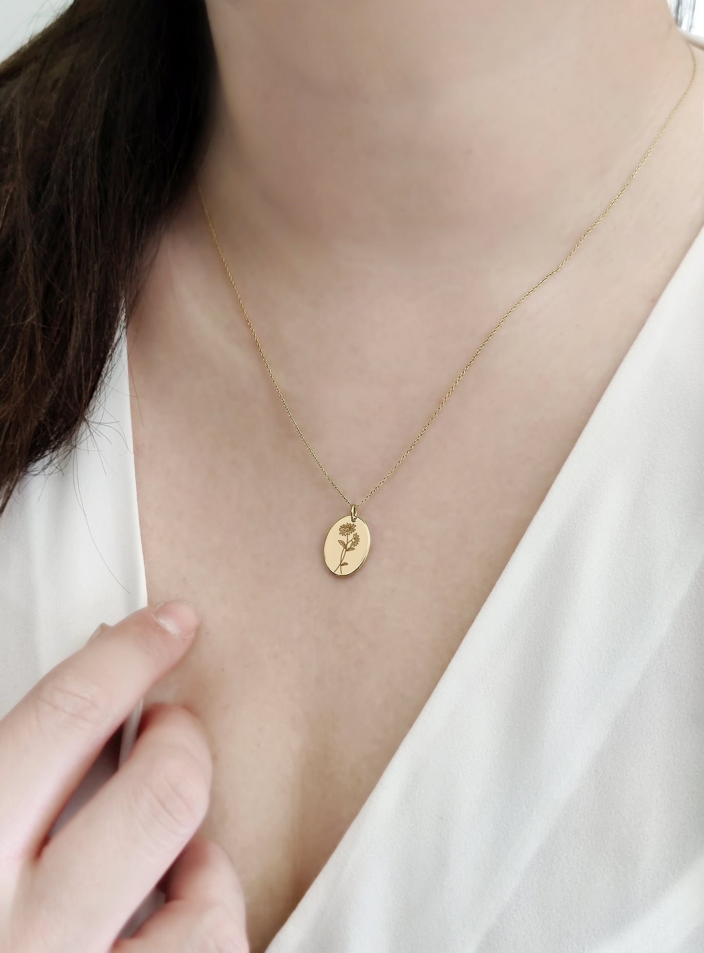female wearing gold oval pendant necklace engraved with Aster birth flower of September 