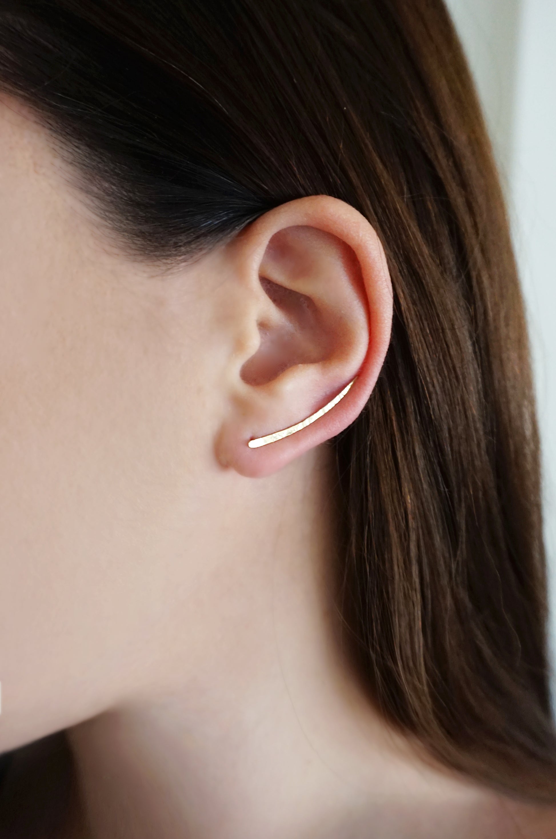close up of a woman's left ear wearing yellow gold climber earring 30mm length with hammered finish