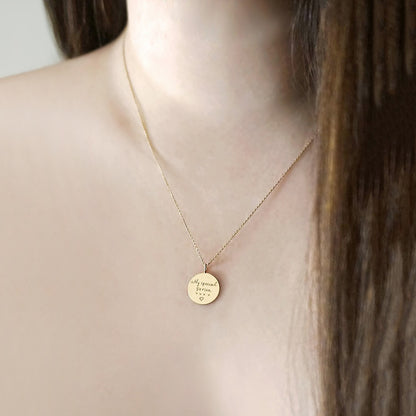 gold necklace with a round pendant with custom handwritten engraving on a female model