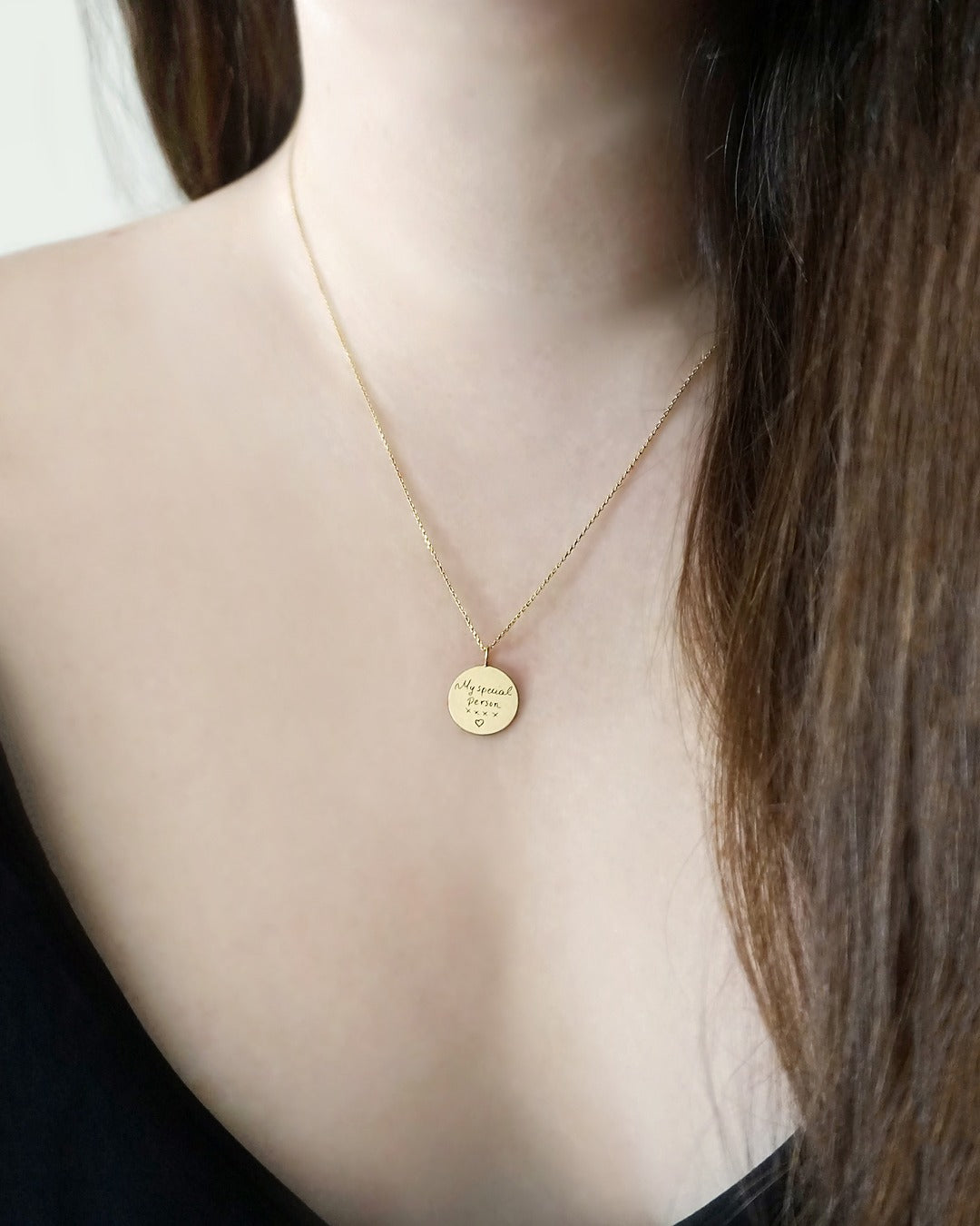 gold necklace with a round pendant with custom handwritten engraving on a female's neck