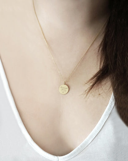 gold necklace with a round pendant with custom handwritten engraving worn by a female model