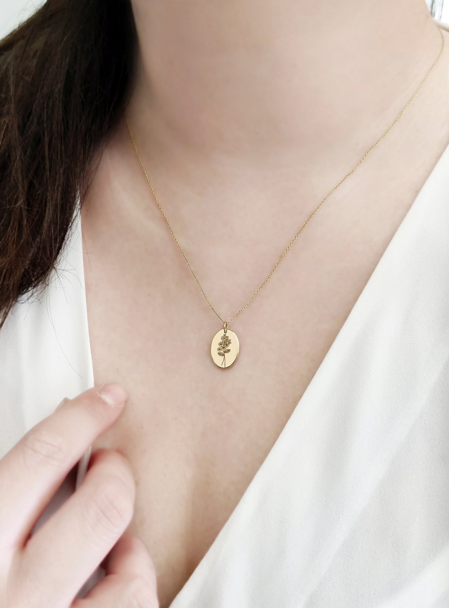 female wearing gold oval pendant necklace engraved with Hawthorn birth flower of May 