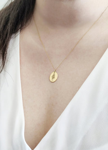 female wearing solid yellow gold oval pendant necklace engraved with a Larkspur the birth flower of July 