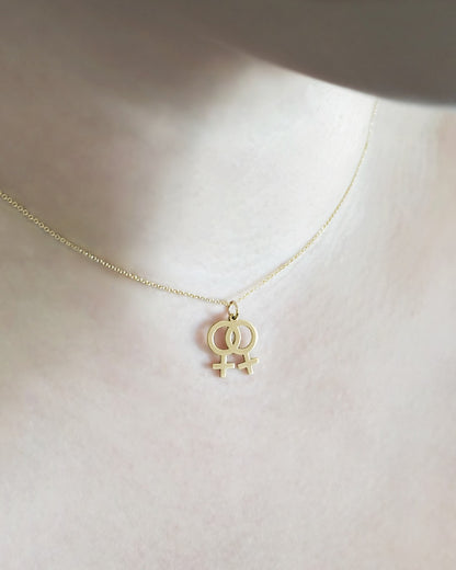 Female wearing gold necklace with a small double female/venus lesbian symbol pendant