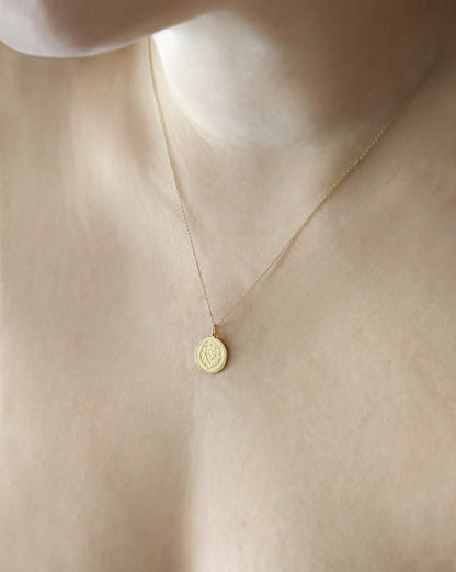 female wearing yellow gold disc pendant necklace engraved with a lion head and a circle frame around it