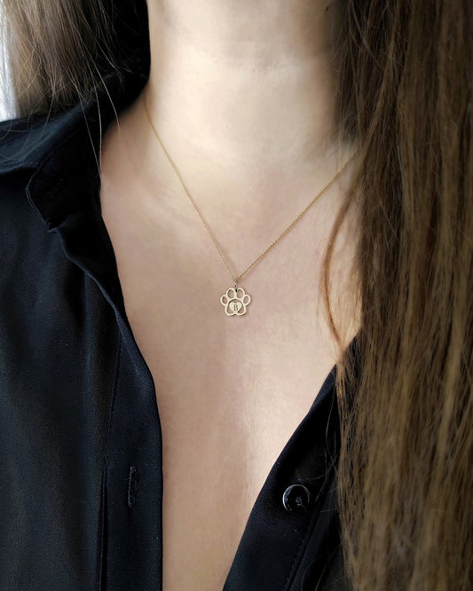 female wearing gold necklace with a dog paw print pendant engraved with a monogram