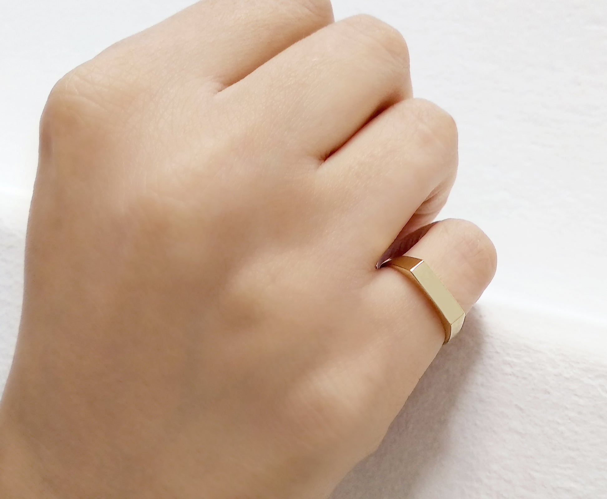 female wearing solid gold rectangle bar signet ring on her pinky