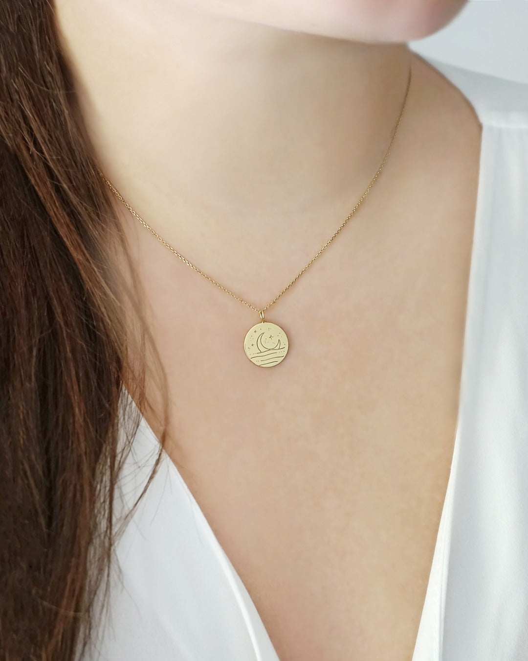 female wearing gold necklace with reversible pendant engraved with a moon on one side and a sun on the other side 