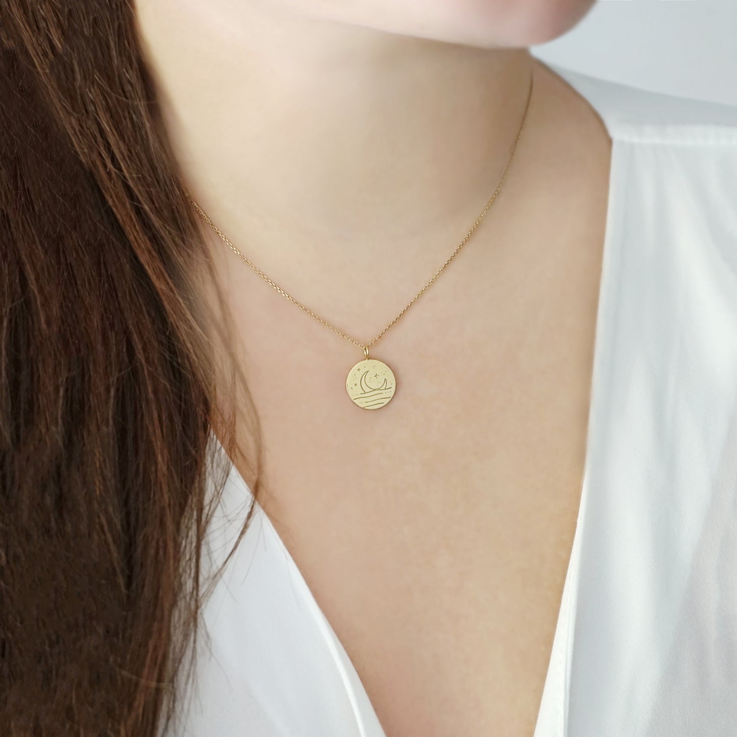 female wearing gold necklace with reversible pendant engraved with a moon on one side and a sun on the other side 