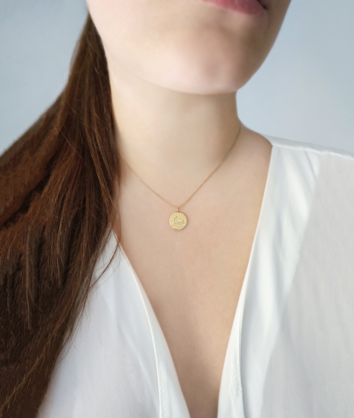 female wearing gold necklace with round pendant engraved with a moon 