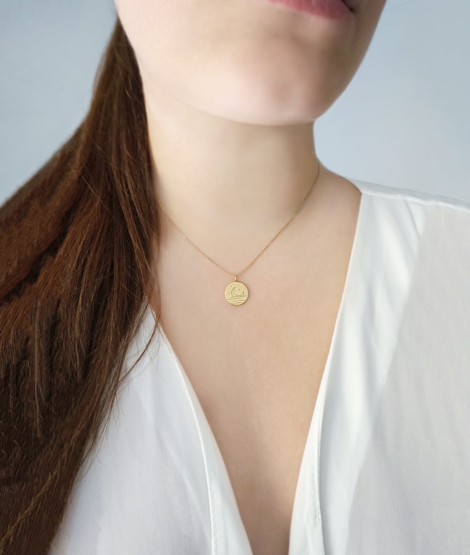 female wearing gold necklace with round pendant engraved with a moon 