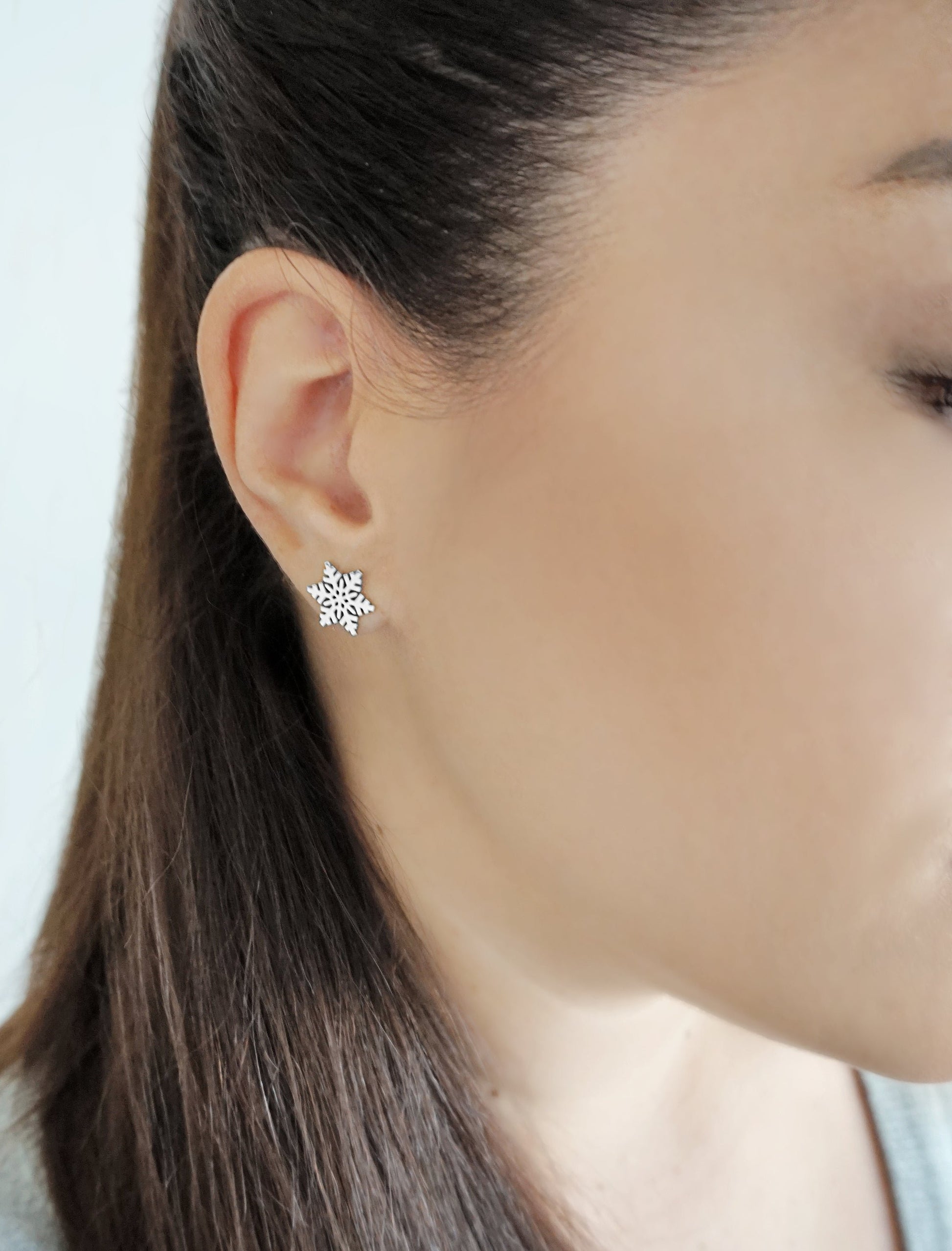 woman wearing white gold stud earring in the shape of a snowflake
