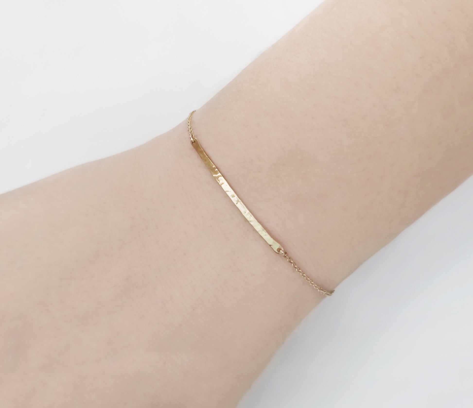 female wearing a solid yellow gold thin hammered bar bracelet