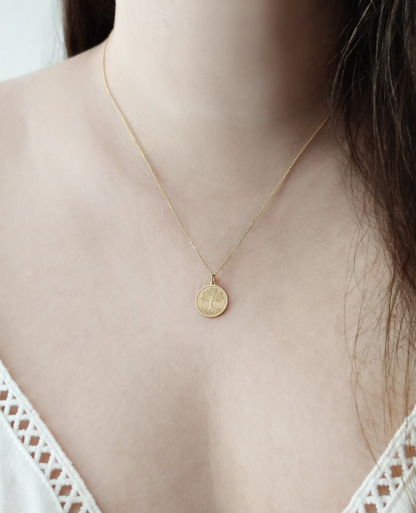 close up of a woman's neck wearing a yellow gold necklace with a 14mm disc pendant engraved with the Tree of Life