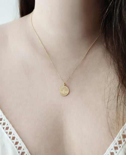 close up of a woman's neck wearing a yellow gold necklace with a 14mm disc pendant engraved with the Tree of Life