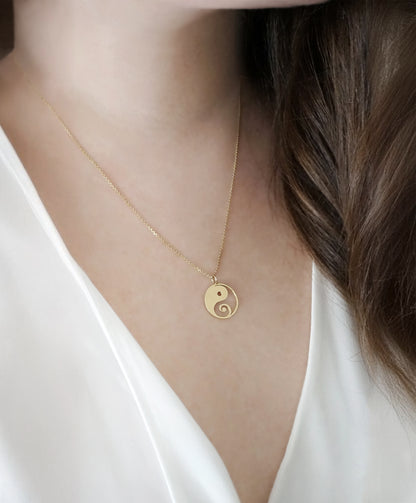 close up of a woman's neck wearing a solid yellow gold necklace with a 16mm yin yang pendant