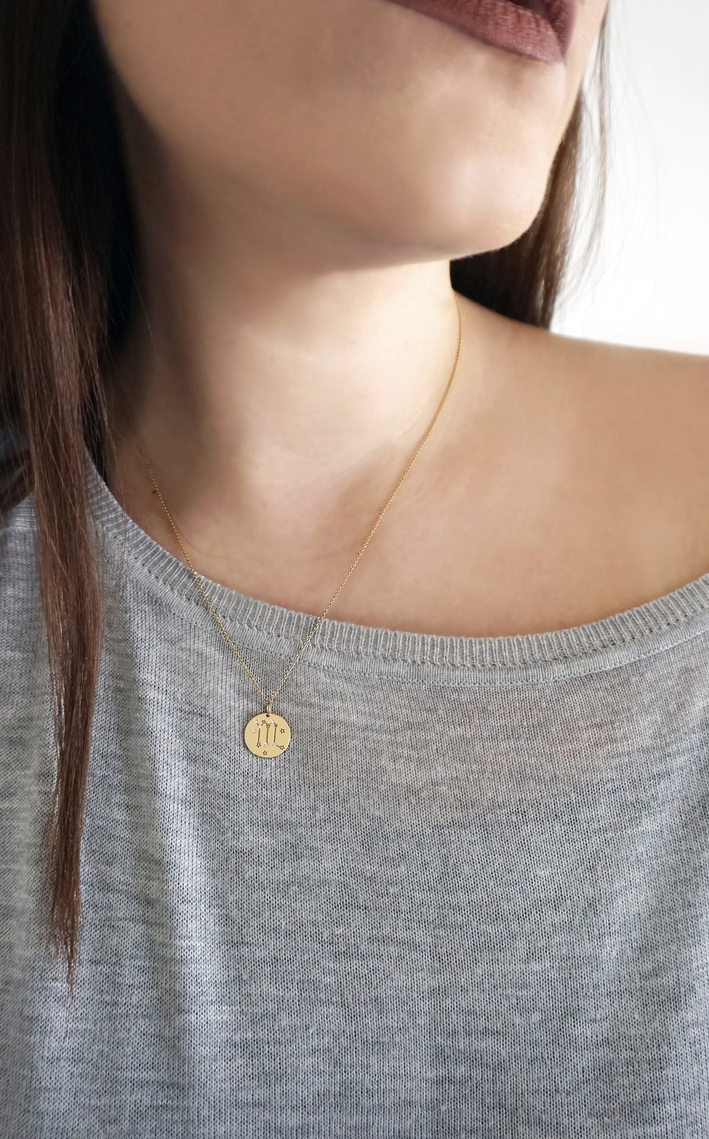 female wearing gold necklace with a 14mm disc pendant engraved with the Scorpio zodiac sign and set with six tiny diamonds