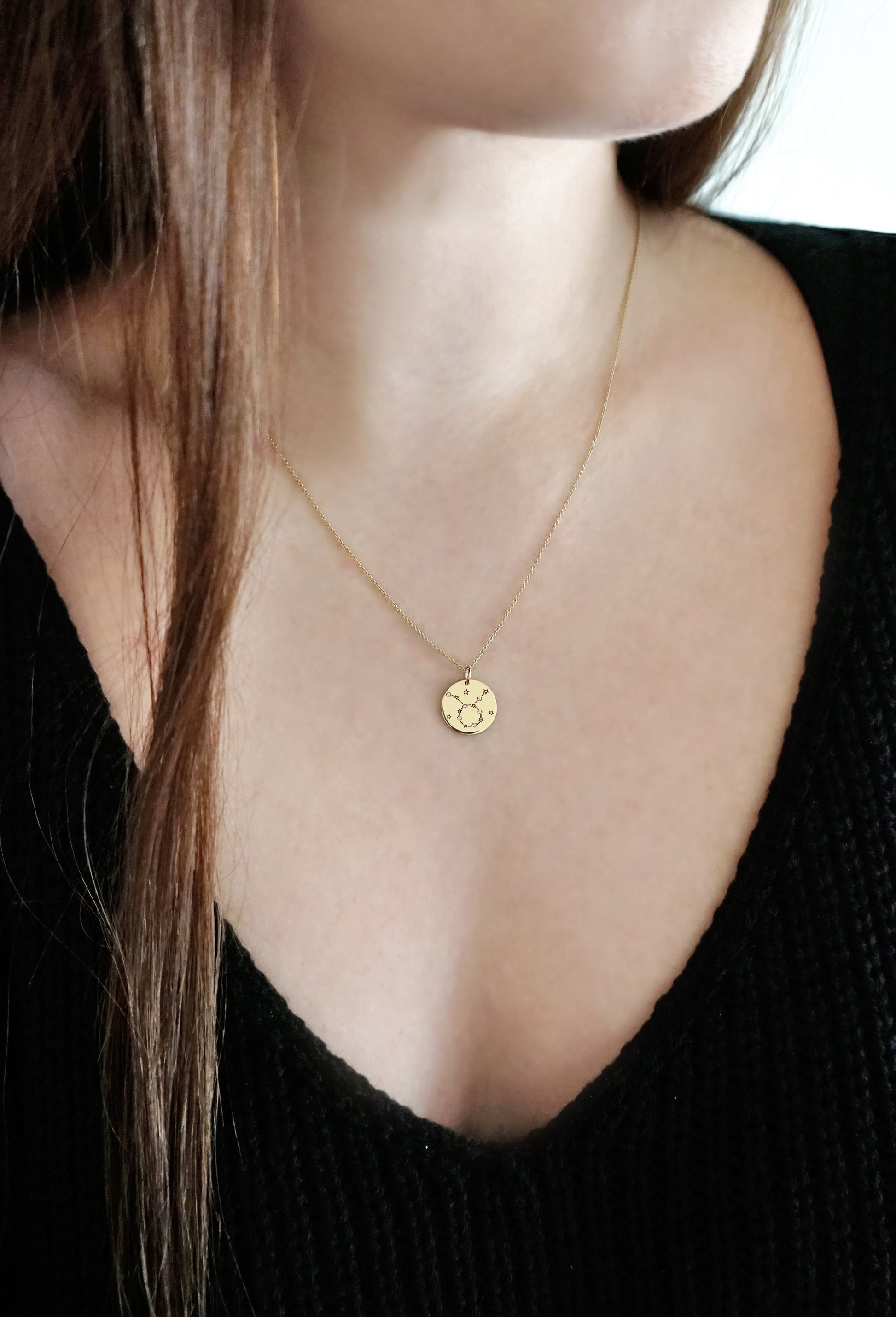 female wearing gold necklace with a 14mm disc pendant engraved with the Taurus zodiac sign and set with six tiny diamonds