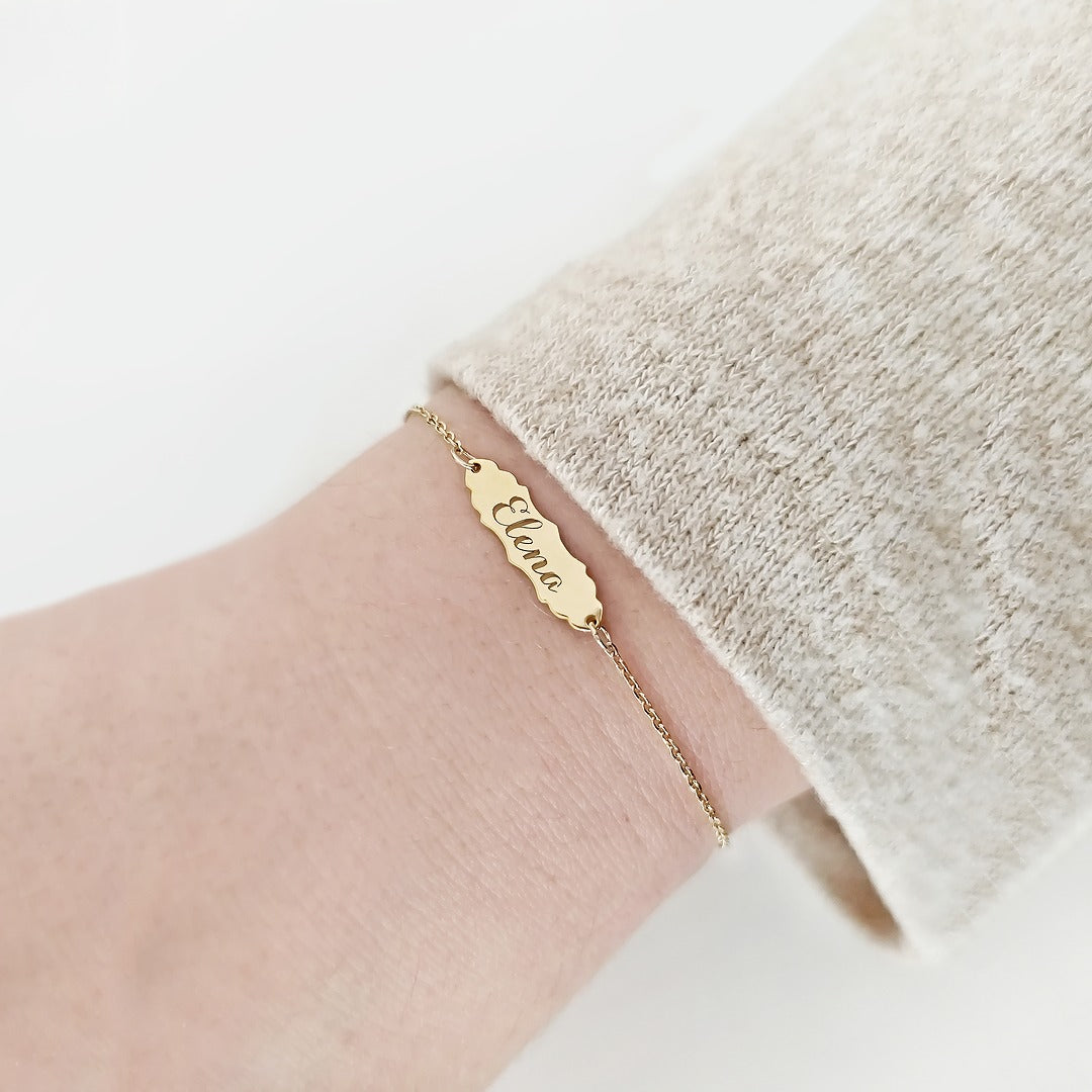 woman wearing gold bracelet with a vintage baroque inspired bar engraved with a name