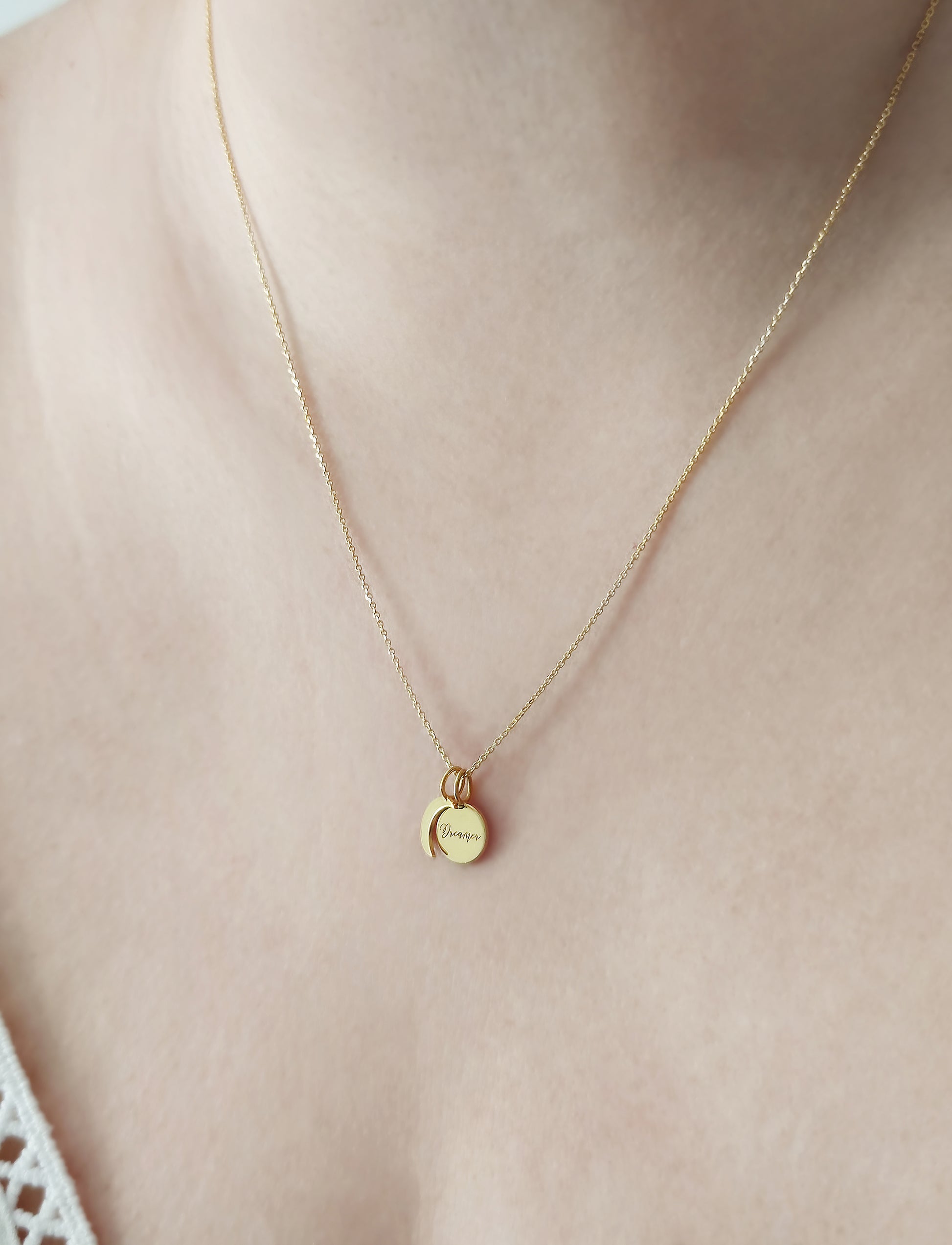 female wearing gold necklace with two small charms, a crescent moon and a personalized disc