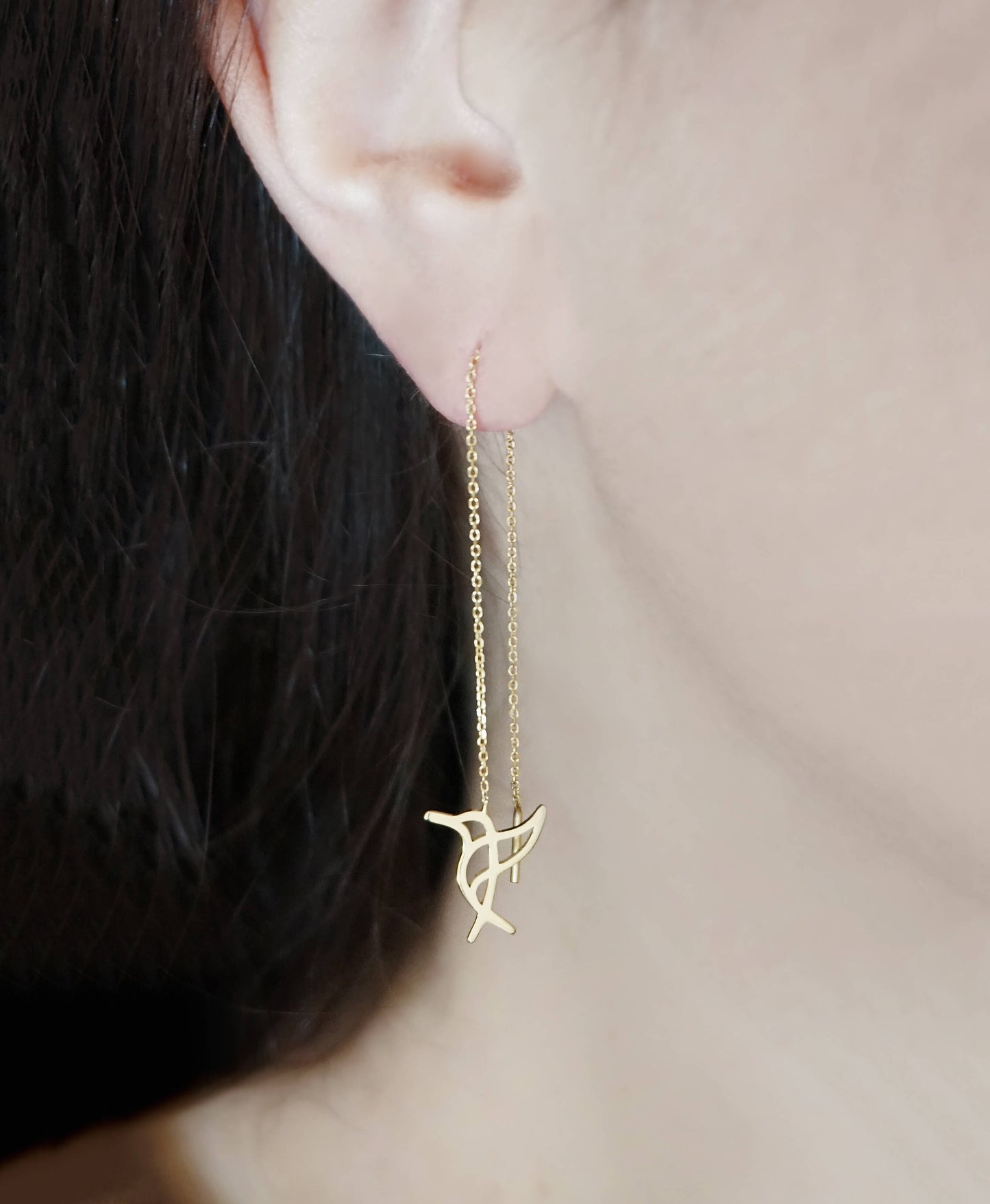 Female wearing yellow gold hummingbird threader earrings