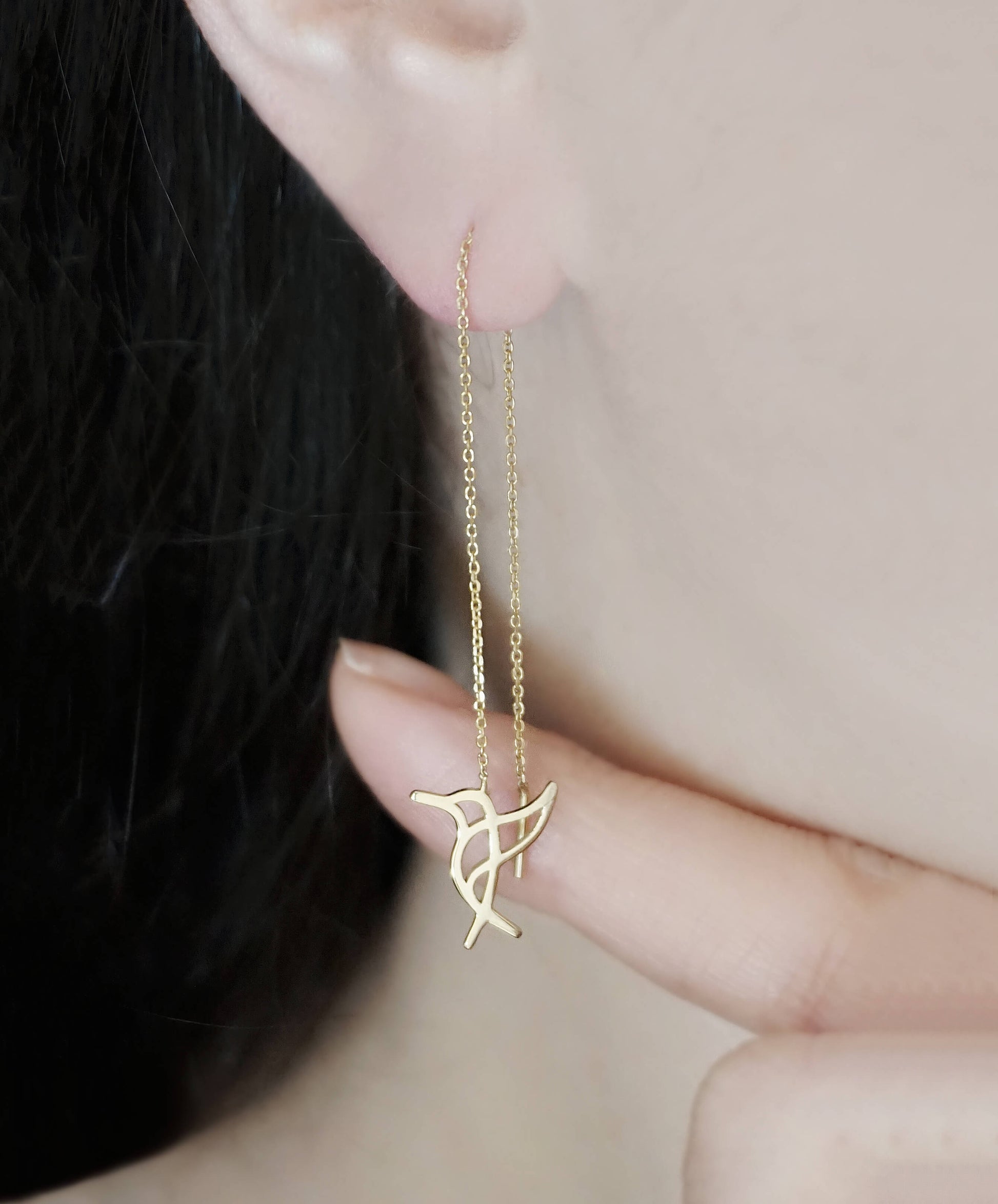 Person wearing yellow gold hummingbird threader earrings