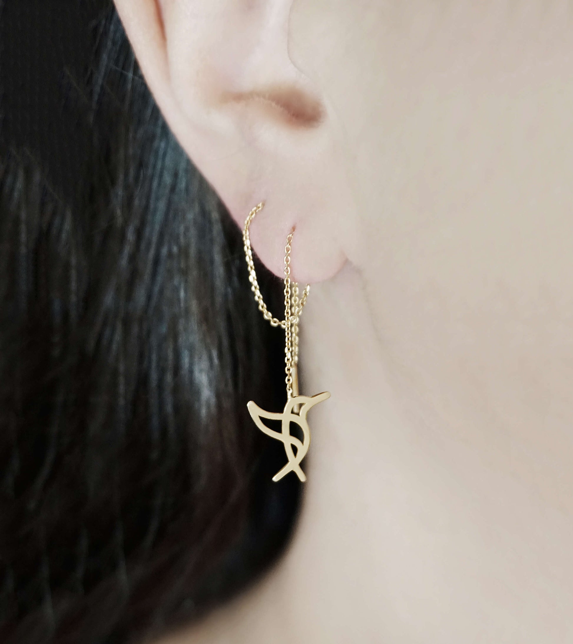 Woman wearing yellow gold hummingbird threader earrings