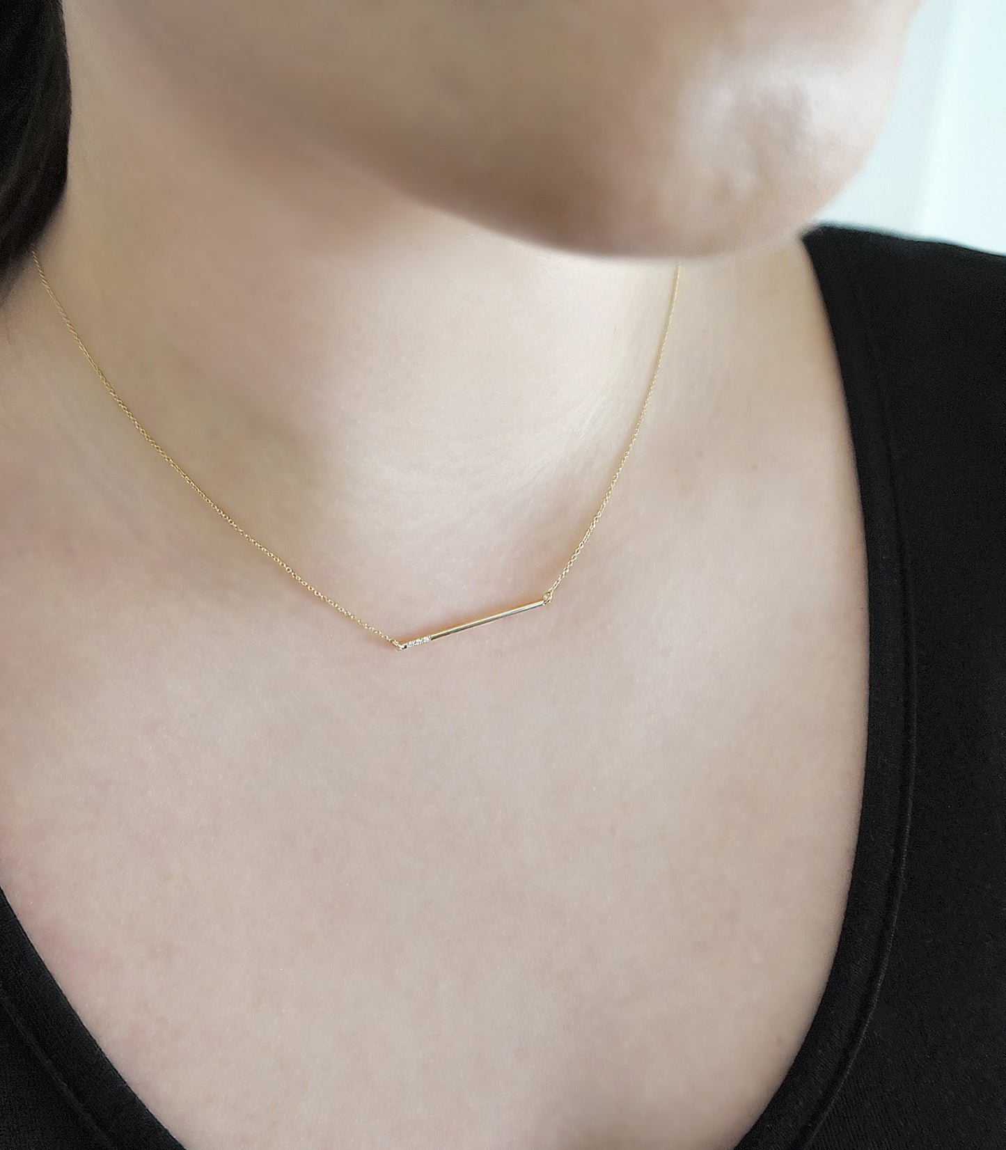 female wearing 14K gold thin bar necklace set with three tiny white diamonds