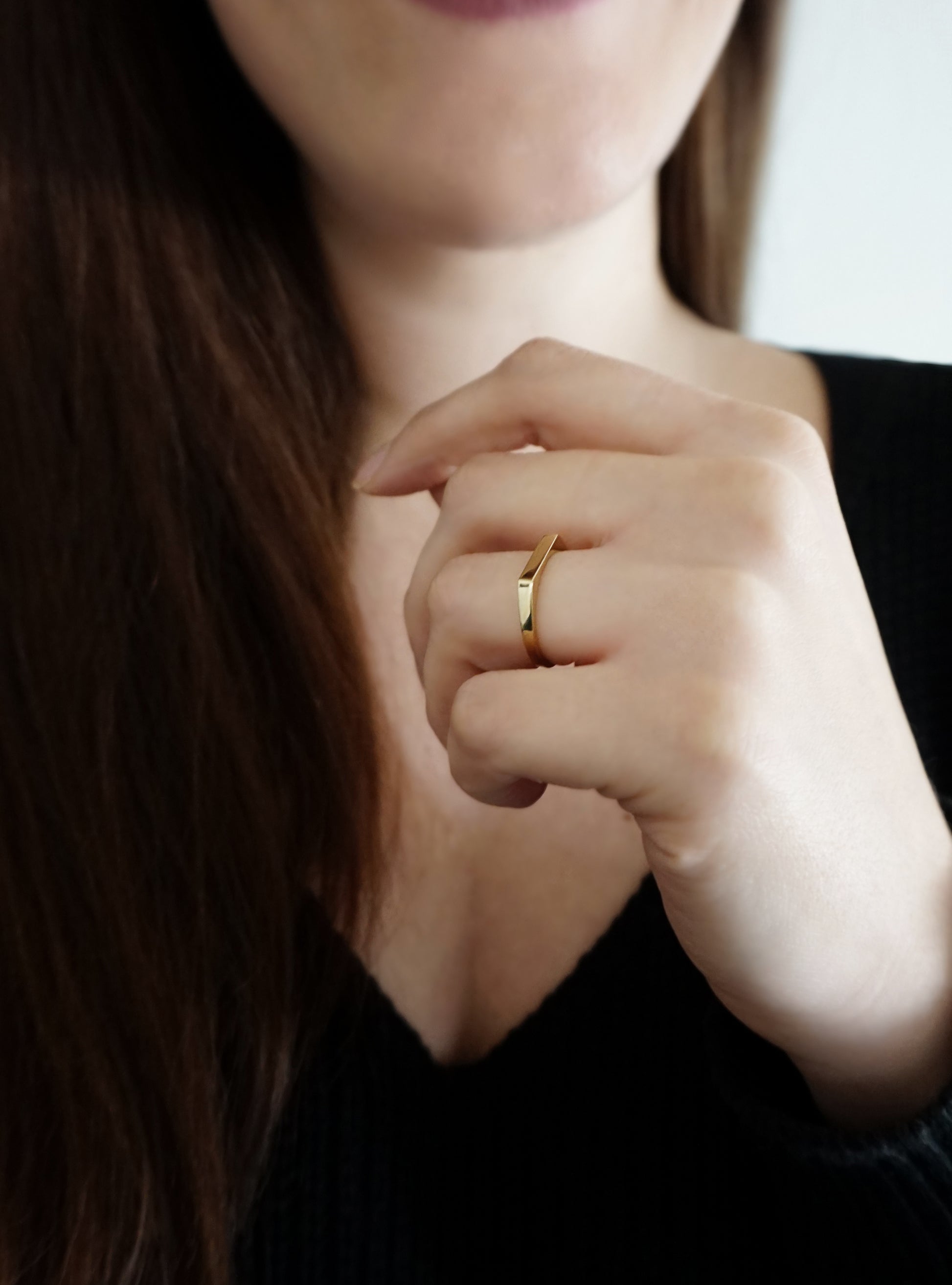 female wearing gold thin bar ring on her ring finger