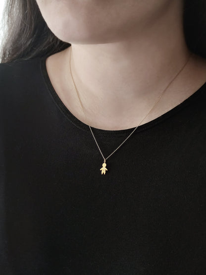 close up of a woman's neck wearing a gold necklace with a tiny boy charm engraved with a monogram and set with a tiny diamond