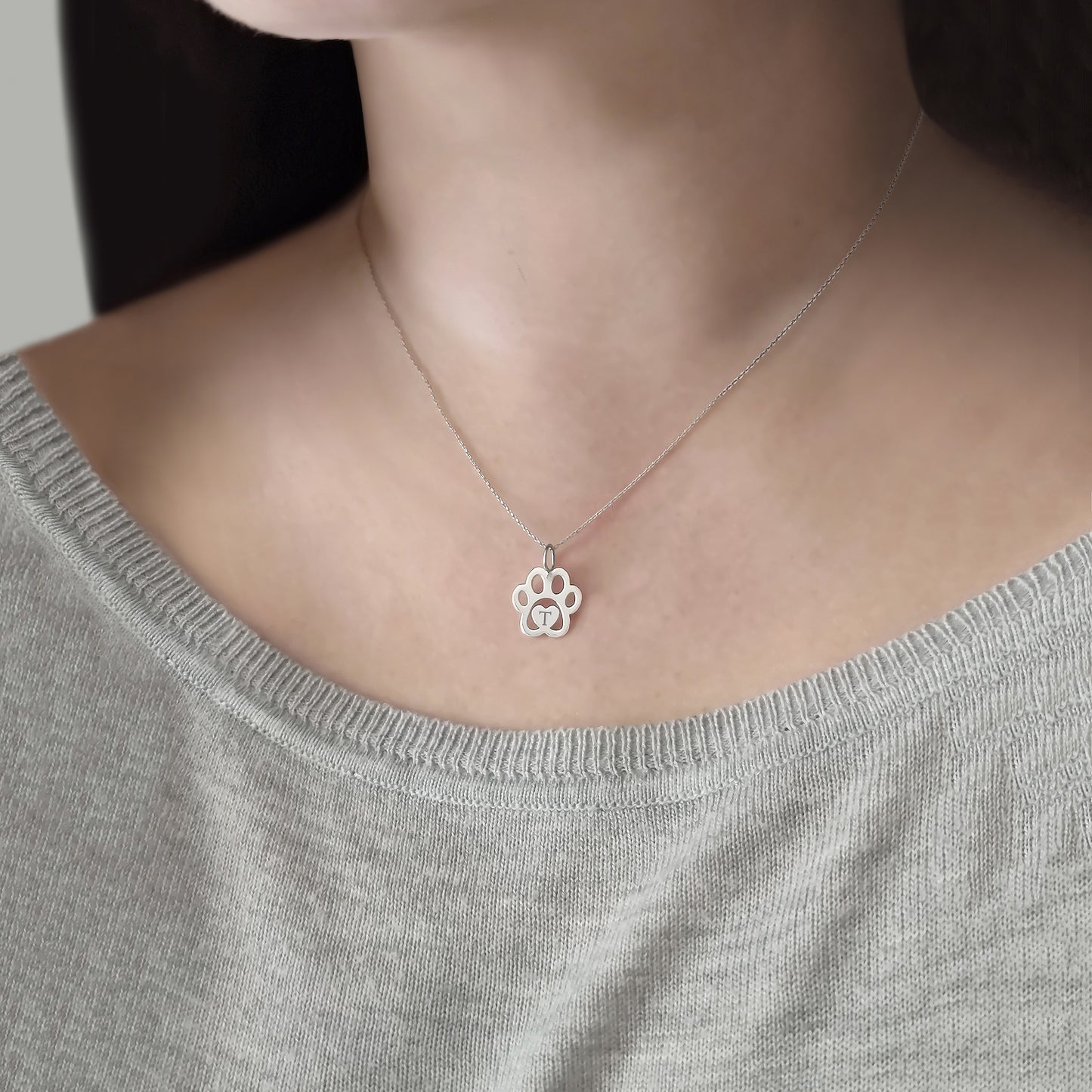 woman wearing gold necklace with a dog paw print pendant engraved with a monogram