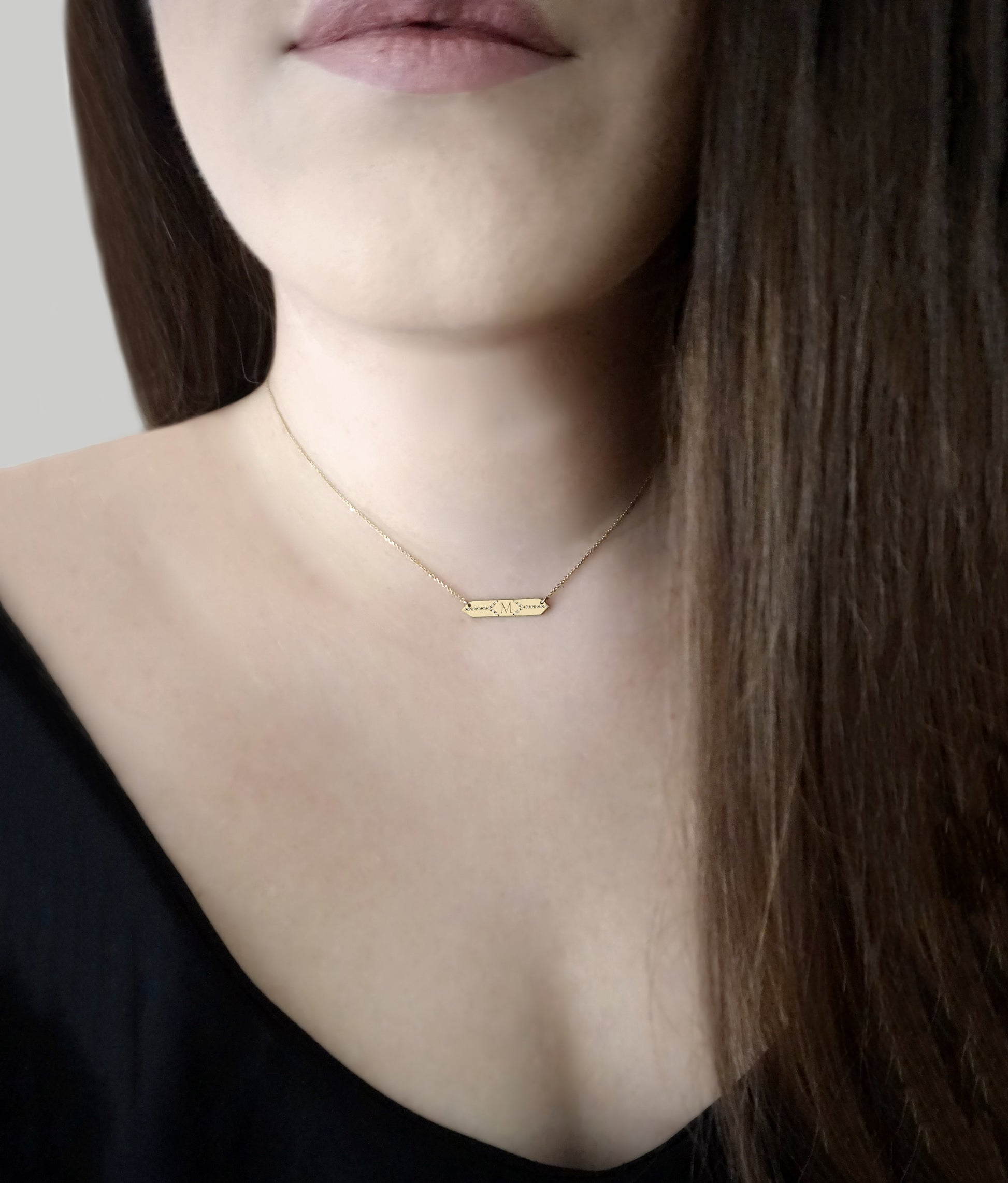 woman wearing a gold hexagon bar necklace set with white diamonds and personalized with a custom monogram