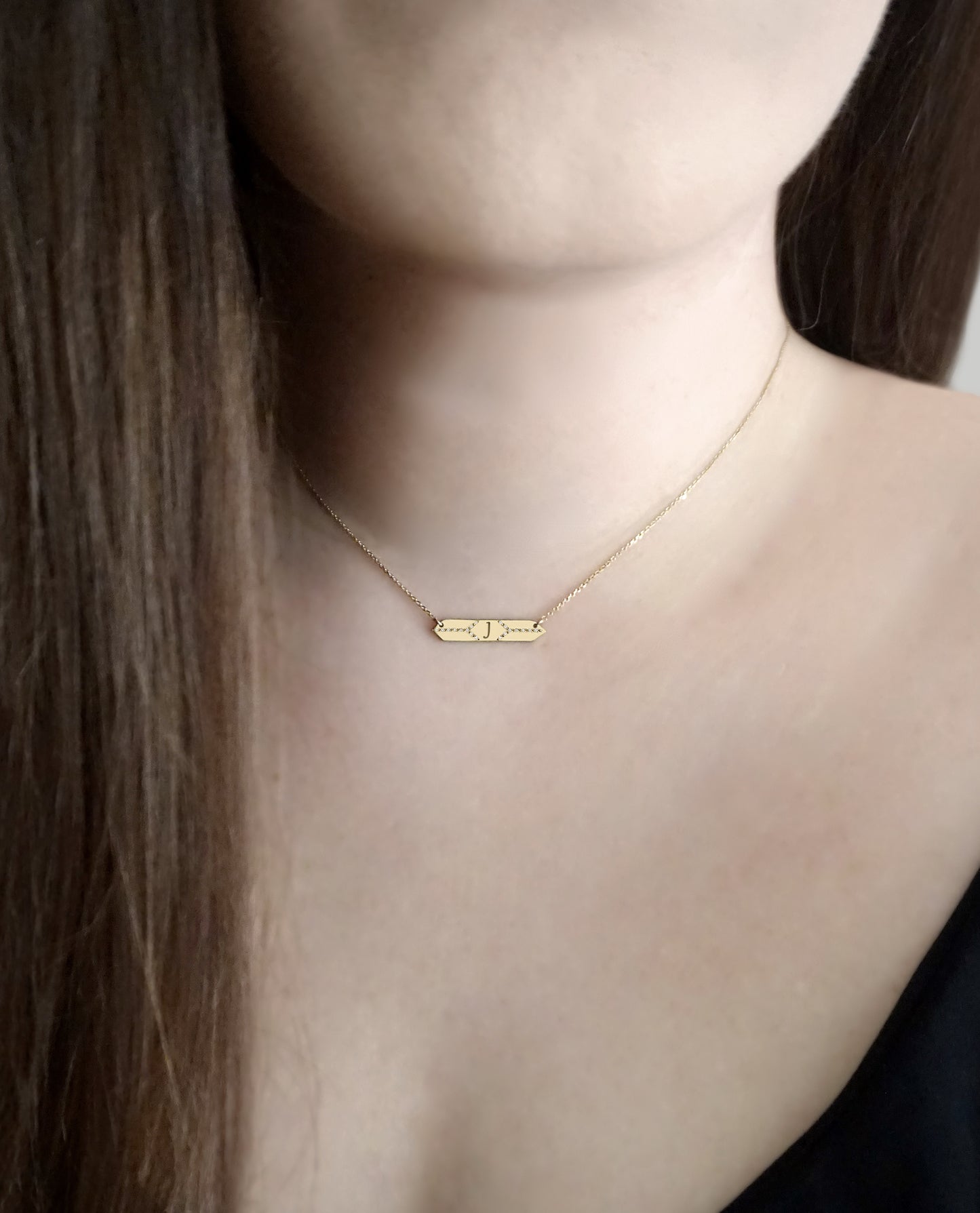 female wearing a hexagon bar necklace set with white diamonds and personalized with a custom monogram