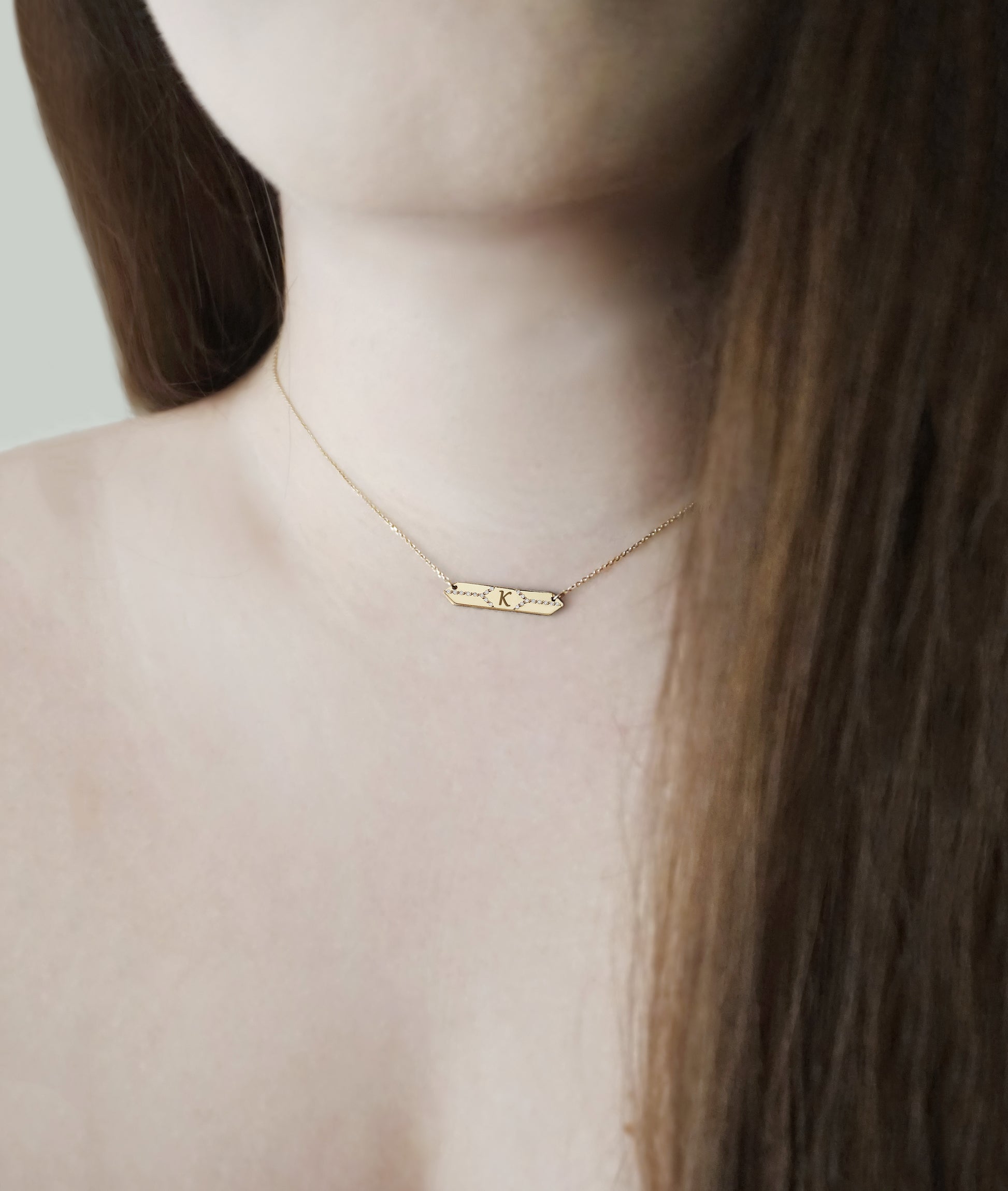 female wearing a solid gold hexagon bar necklace set with white diamonds and personalized with a custom monogram