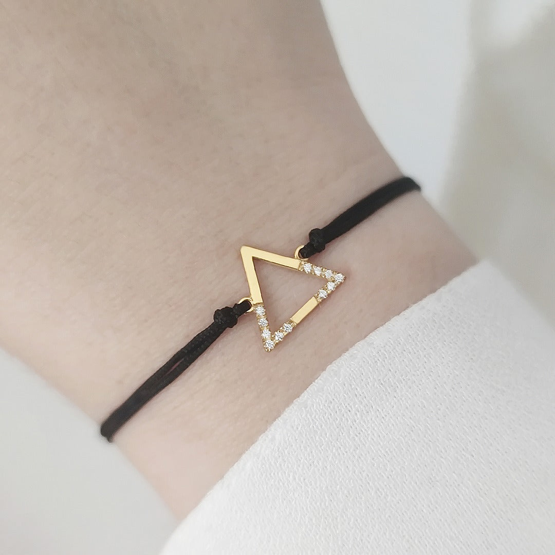 woman's wrist wearing solid yellow gold macrame bracelet with a small triangle charm set with 12 white diamonds on its two corners