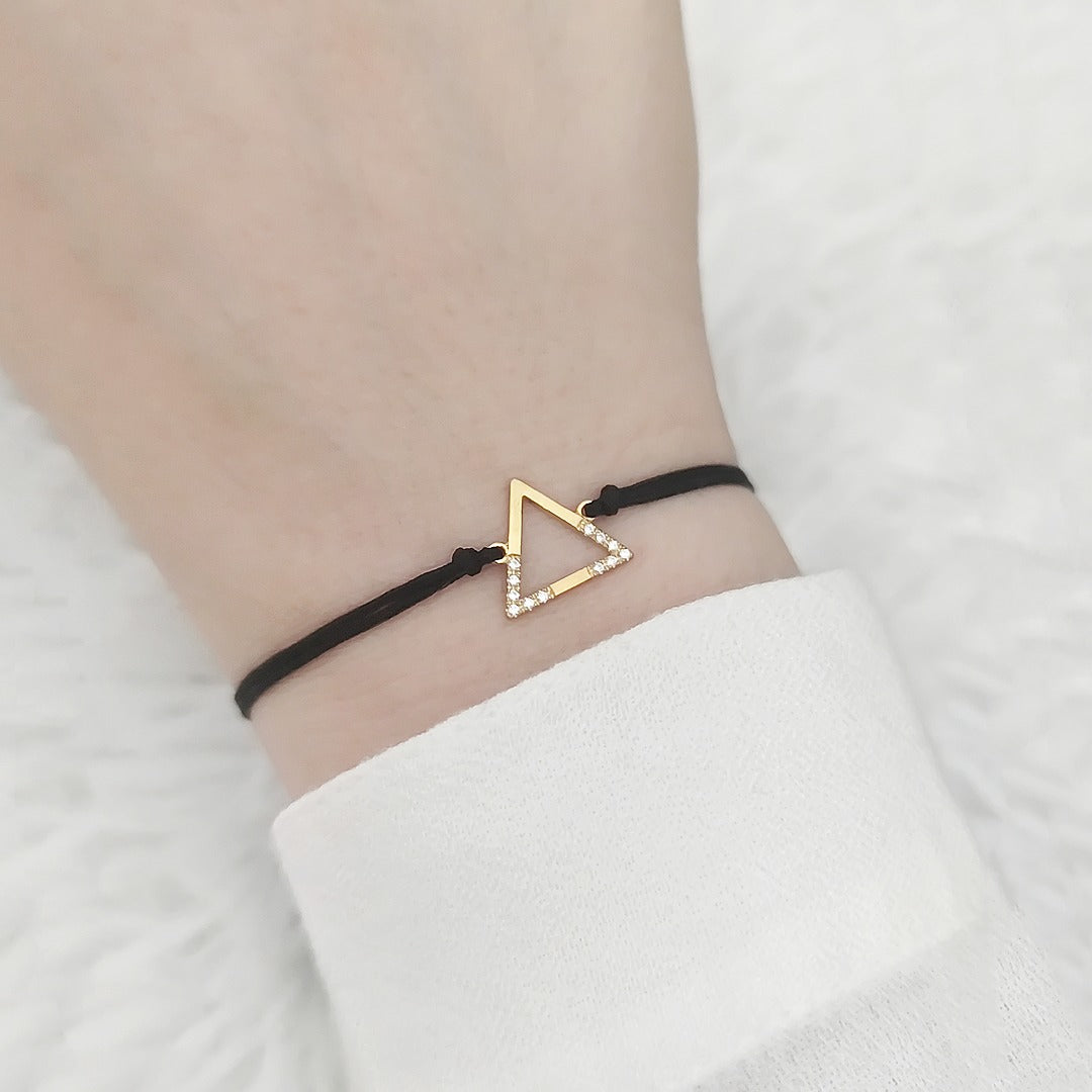 female wrist wearing solid yellow gold macrame bracelet with a small triangle charm set with 12 white diamonds on its two corners