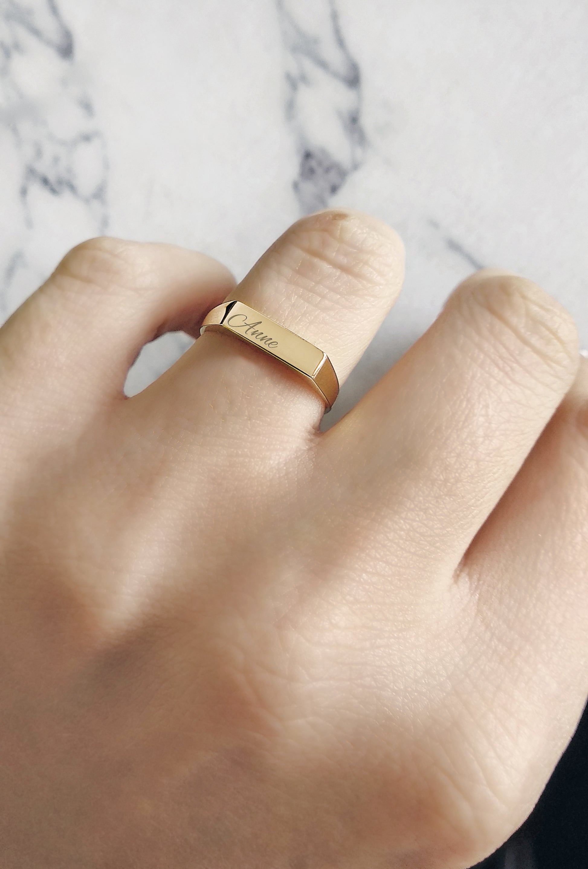 woman's hand wearing solid yellow gold rectangle bar signet ring on her ring finger personalized with engraving