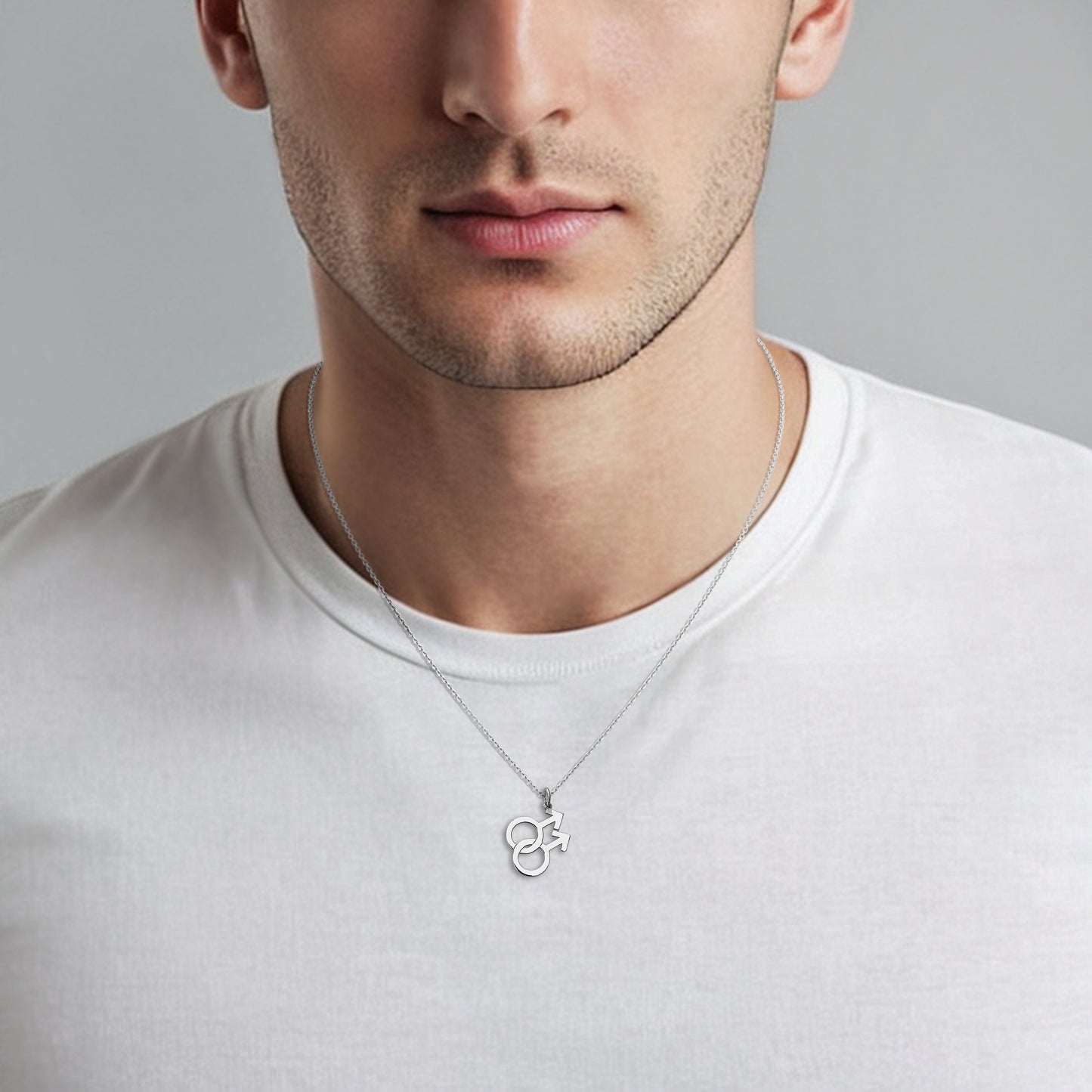Man wearing a white gold necklace with a double mars symbol pendant against a gray background