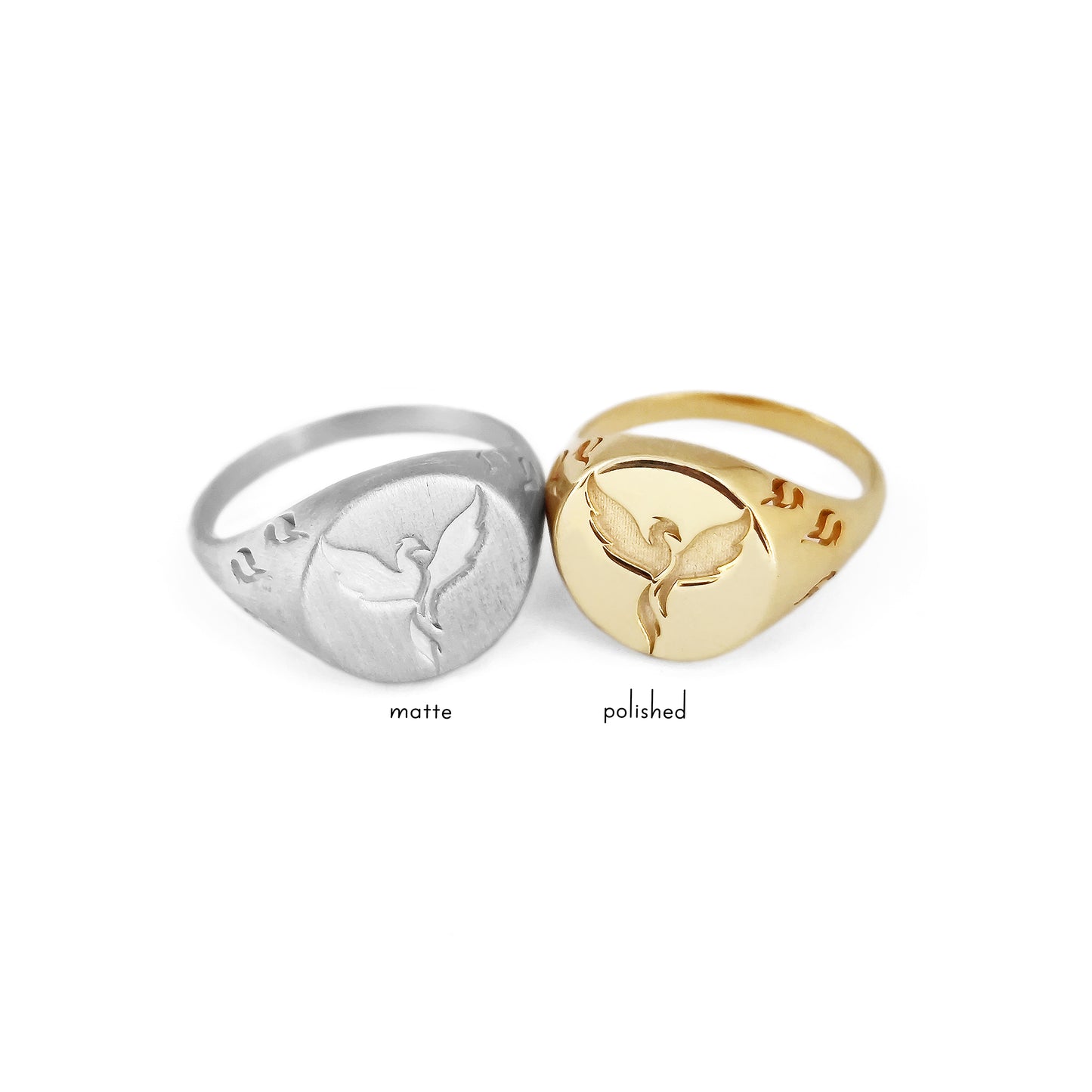 matte solid white gold and polished solid yellow gold round signet rings engraved with a phoenix firebird rising with flame cutouts around the base of the ring's head