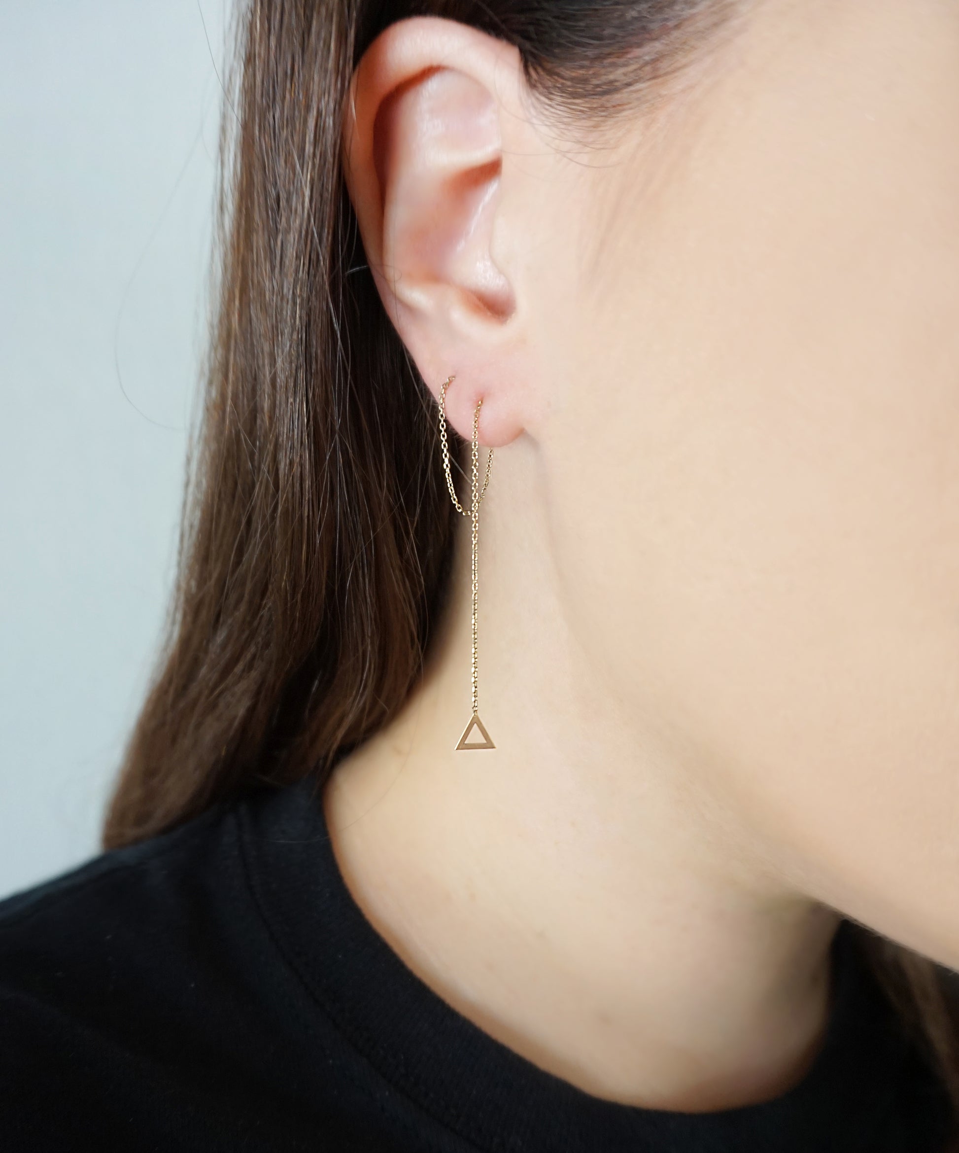 woman wearing solid yellow gold threader earring with a tiny triangle pulled through two piercings