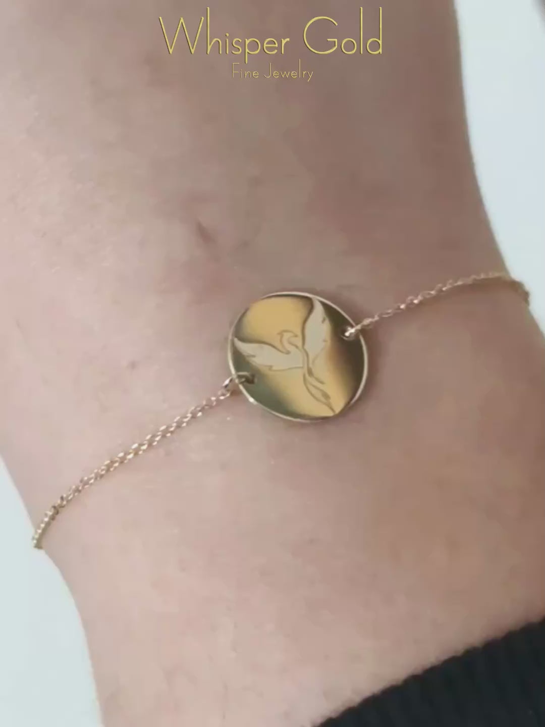 video of a gold bracelet with a 14mm disc charm engraved with a phoenix firebird rising