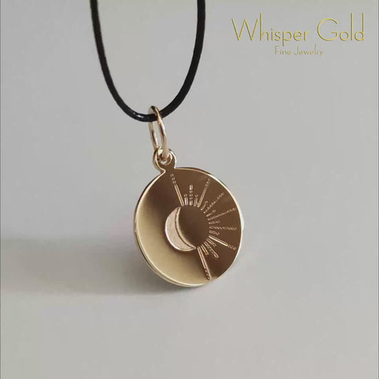 video of a solid gold disc pendant engraved with a sun and moon design