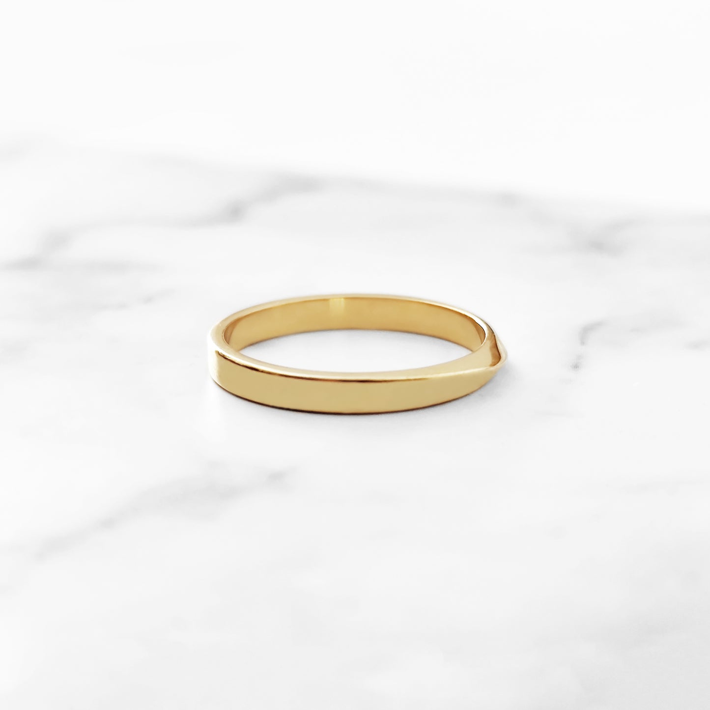 side view of a polished solid yellow gold thin mobius wedding ring 